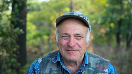 Portrait of middle-aged man. The old man is smiling and happy. In the background of green forest.