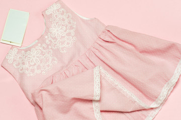 Clothes for baby girl on a pink background. Copy space