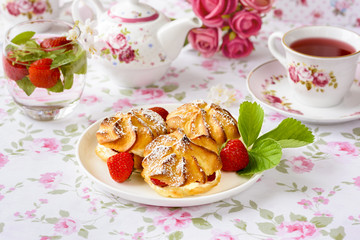 Cream puff cakes or profiterole filled with whipped cream, served with strawberries
