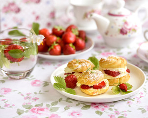 Cream puff cakes or profiterole filled with whipped cream, served with strawberries