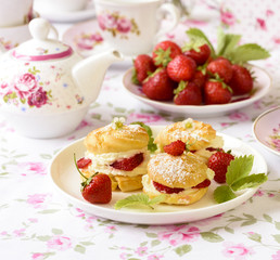 Cream puff cakes or profiterole filled with whipped cream, served with strawberries