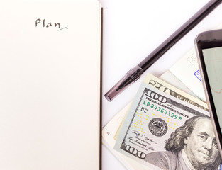 Paper money, passport, phone and pen for travel plan with copy space on blank notebook