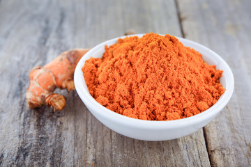 whole and turmeric powder on wooden table