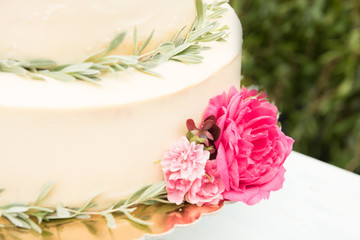 Beautiful wedding cake with flowers on table, outdoors. Close-up