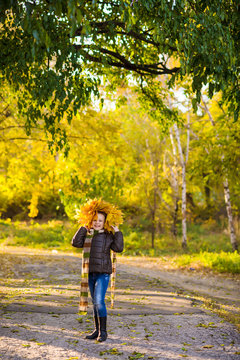 a teenager girl in jacket and jeans plays in the autumn park with golden leaves