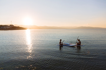 Fototapeta premium Silhouette of male and female in yoga pose on sup surf swimming at the ocean. Concept lifestyle, sport, love