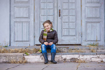 old grey doors and a little girl sitting on the ground