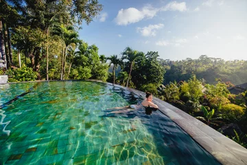 Fotobehang Bali portret van mooie vrouw in luxe resort. Jong meisje dat een bad neemt en ontspant bij het oneindige zwembad