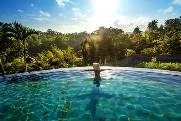 Wall murals Bali happiness concept. Woman sunbathing in infinity swimming pool at
