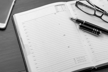 Notebook with glasses, pen and smart phone on wooden background.