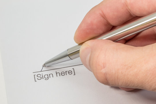 Hand signing a contract with a silver pen