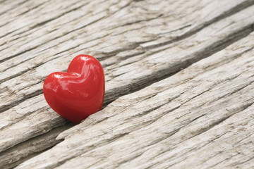 Fototapeta premium Glossy red heart in crack on an old wooden surface