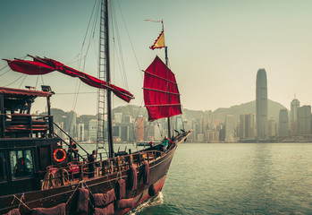 Scenic skyline of a big city with skyscrapers and old traditional boat. Victoria harbor. Famous landmark of Hong Kong. Vintage effect.