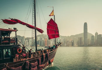 Foto op Canvas Scenic skyline of a big city with skyscrapers and old traditional boat. Victoria harbor. Famous landmark of Hong Kong. Vintage effect. © Funny Studio