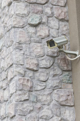 The CCTV security camera operating on stone brick wall.