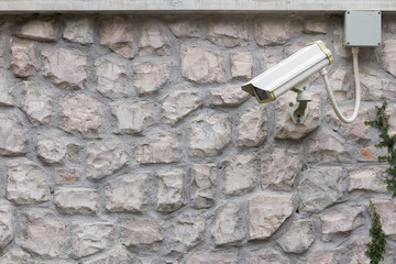 The CCTV Security Camera operating on stone brick wall.