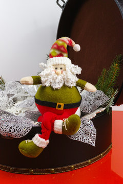 Santa Claus sits on vintage brown coffer with white christmas tree