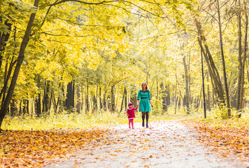 Mother and daughter walking holding hands at park. Family lifestyle, autumn season concept