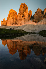 Famous mountain peaks of Tre Cime and their reflection on a still lake at sunset. Amazing Landscape of Dolomites range. Fantastic hike. Peaceful feeling.