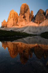 Famous mountain peaks of Tre Cime and their reflection on a still lake at sunset. Amazing Landscape of Dolomites range. Fantastic hike. Peaceful feeling.