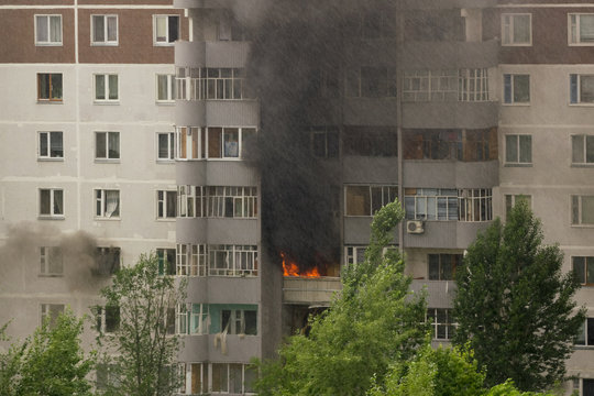 Fire with black smoke in multistory apartment building. Toned