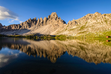 Famous mountain peaks of Tre Cime and their reflection on a still lake at sunset. Amazing Landscape of Dolomites range. Fantastic hike. Peaceful feeling.