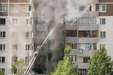 Fototapeta na wymiar Firefighters extinguish a fire in multistory apartment building
