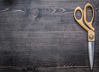 Metal golden scissors on vintage wooden board copy space