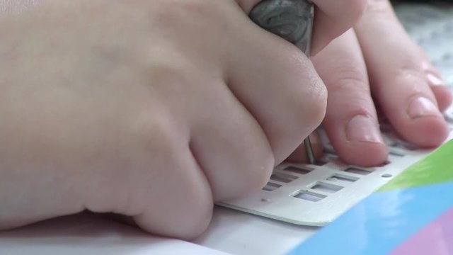 Kid Writing Braille. The child learns to write in Braille on a sheet of paper sitting at the desk in the school special needle