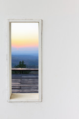 White wall window with sunset mountain view.
