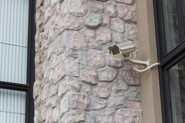 The CCTV security camera operating on stone brick wall.