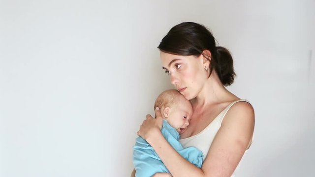 Sad woman holding a newborn son in the hands