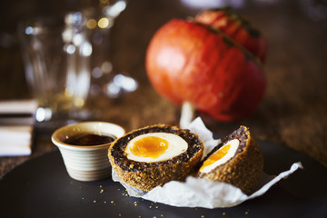 Village public house food. A dish with a fresh made scotch egg cut in to two and a pot of sauce. 