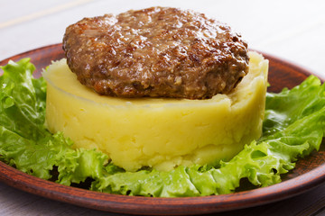 Beef and pork sausage patty with smashed potatoes and lettuce