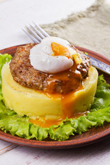 Beef and pork sausage patty with poached egg, smashed potatoes and lettuce