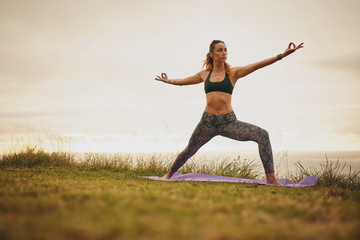 Fit young woman doing yoga on cliff