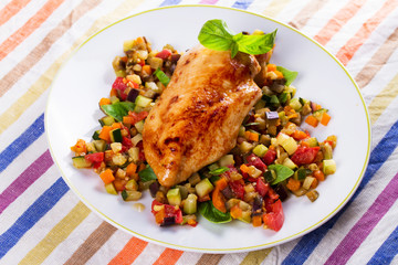 Fried chicken breast with sauteed vegetables: eggplant, carrot, zucchini, squash and tomatoes. View from above, top studio shot