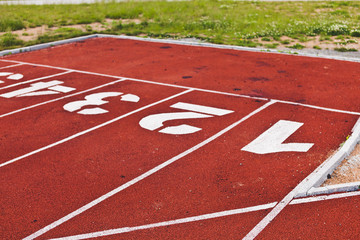 Rugged starting line with digits on stadium, red running path