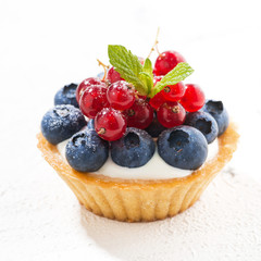 mini tart with cream and berries on white background, closeup