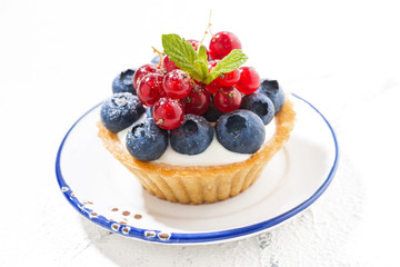 mini tart with cream and berries on white plate