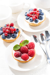 mini tarts with cream and berries on white background, vertical