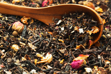 Close up of wooden spoon in pile of dry tea. Selective focus on blurry background