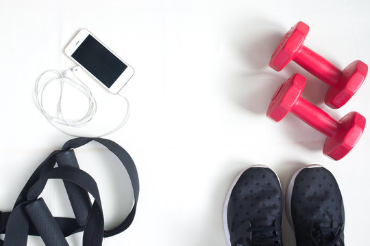 Flat lay of cellphone, red dumbbells and sport equipment on whit