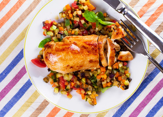 Fried chicken breast with sauteed vegetables: eggplant, carrot, zucchini, squash and tomatoes. View from above, top studio shot