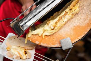 Raclettekäse wird auf Brot geschabt, Delikatesse aus der Schwei