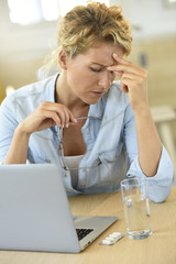 Woman at work taking pill to ease headache