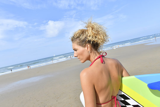 Beautiful surfer girl holding surfboard at the beach