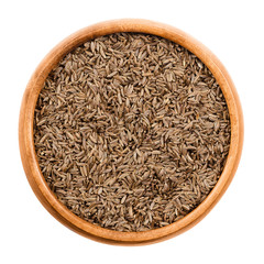 Caraway seeds in wooden bowl on white background. Dried whole fruits of Persian cumin, Carum carvi, with anise like flavor and aroma used as spice in cuisine. Isolated macro photo close up from above.