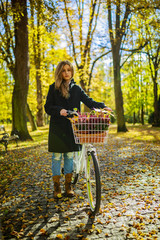 Happy active teenager riding bike in fall autumn park. Young gir
