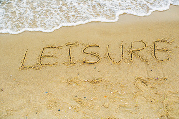 Fototapeta premium Word leisure written on the beach sand; vacation concept